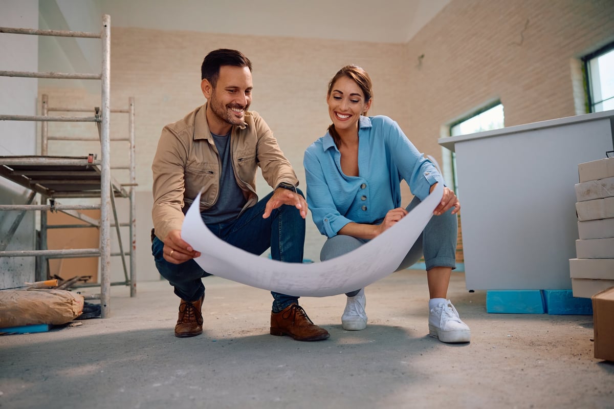 Happy couple reviewing renovation plans with contractor at home