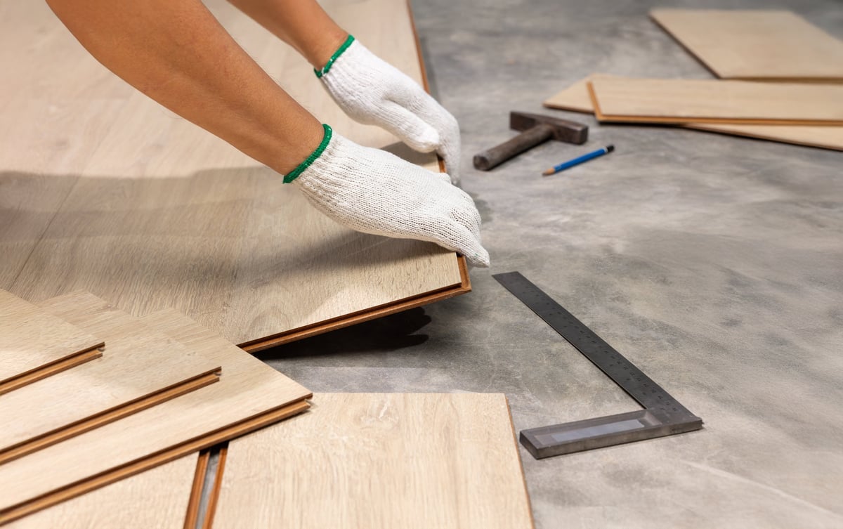 Worker installing interlocking laminate floor during home renovation