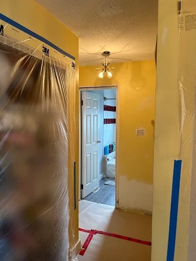 Chilliwack bathroom renovation in progress with yellow walls, shower enclosure with plastic sheeting and floor protection tape