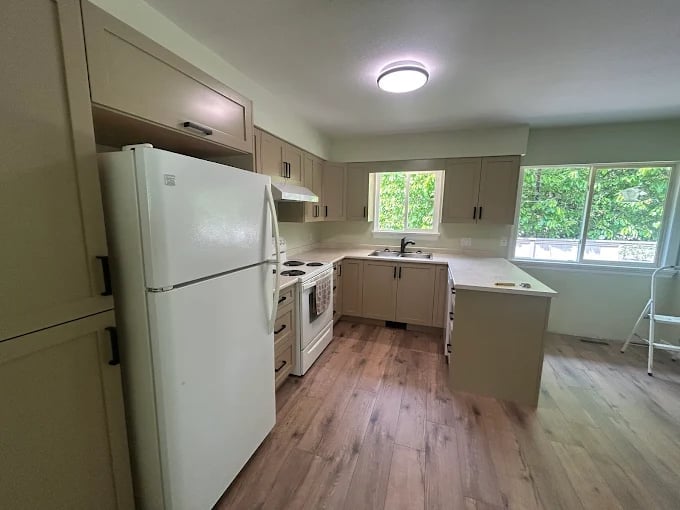 Spacious kitchen with white appliances, beige cabinetry, island counter