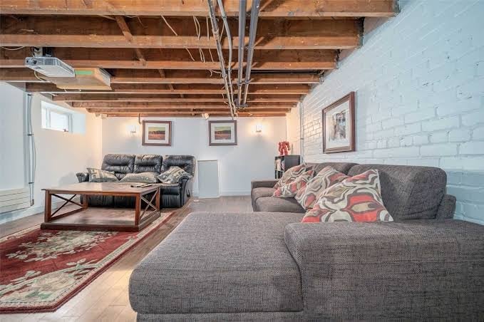 Modern basement living room with gray sectional sofa and exposed wooden ceiling beams