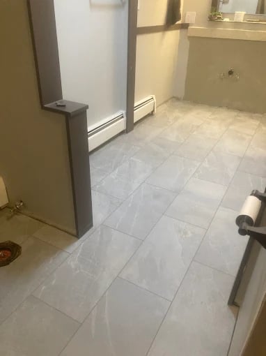 Bathroom remodeling and renovation by our Chilliwack handyman featuring white tile flooring and modern shower stall