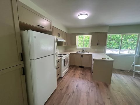 Chilliwack kitchen renovation completed with spacious layout, white appliances, wooden cabinets, laminate flooring and scenic windows
