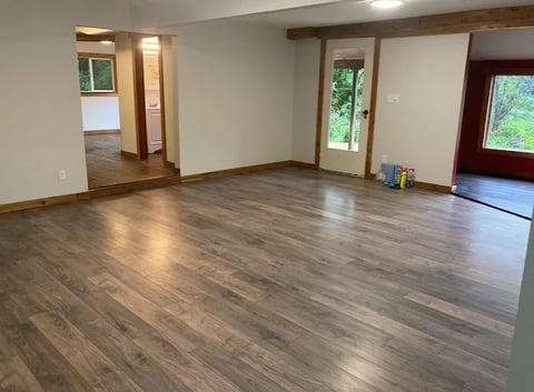 Chilliwack home renovation living room with wood laminate flooring, white walls, exposed wooden beams and glass doors leading to outdoor space